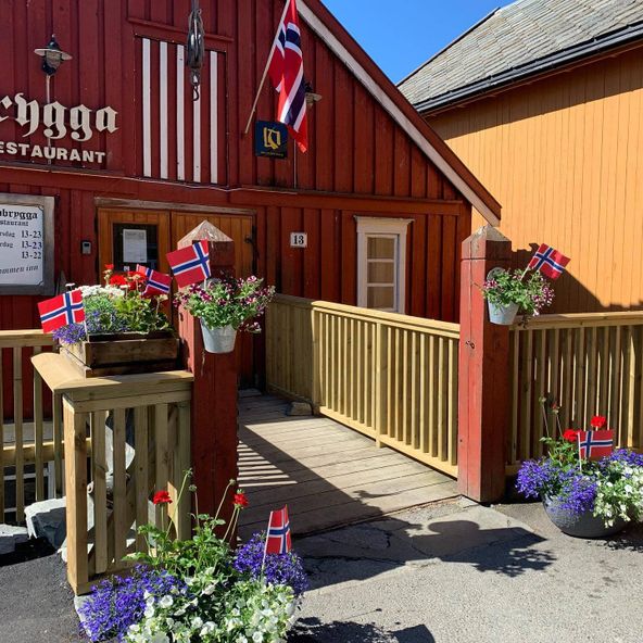 Inngang til restaurant dekorert med blomster og norske flagg