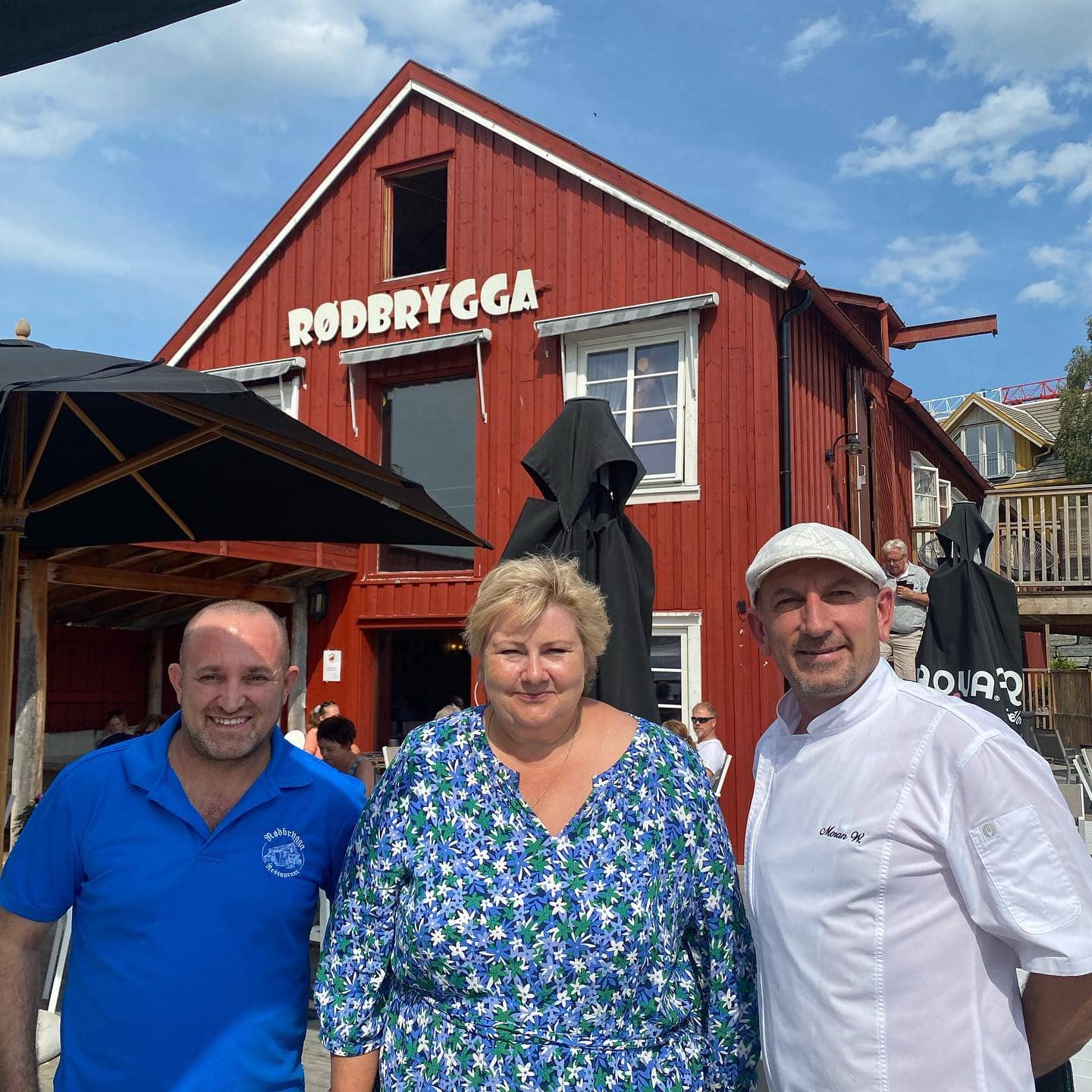 To menn og en kvinne (restauranteiere og Erna Solberg) som smiler til kamera